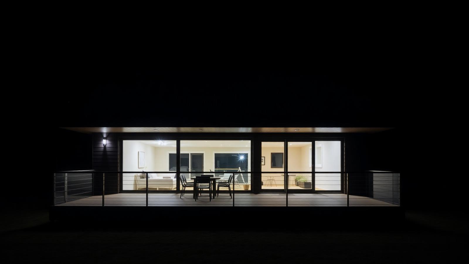 Completed Taupō home at night with warm interior light spilling across the terrace